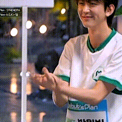 a young man in a white shirt with green sleeves is clapping his hands