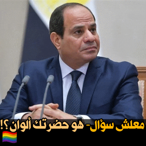 a man in a suit and tie sitting in front of microphones