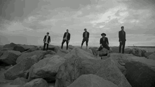 a group of men in suits are standing on rocks