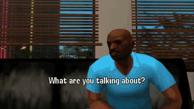 a man in a blue shirt is sitting on a couch and talking about something