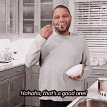 a man is eating cereal in a kitchen with a spoon .