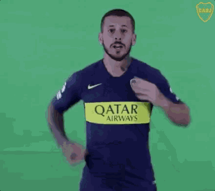 a man with a beard is wearing a blue and yellow qatar airways jersey and dancing .