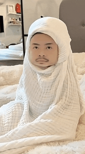a man is wrapped in a white blanket with his face wrapped in it