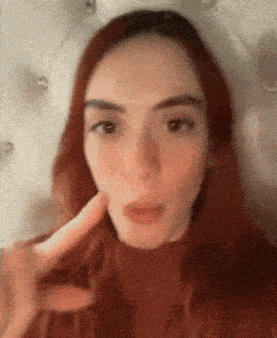 a close up of a woman 's face with her hand on her chin