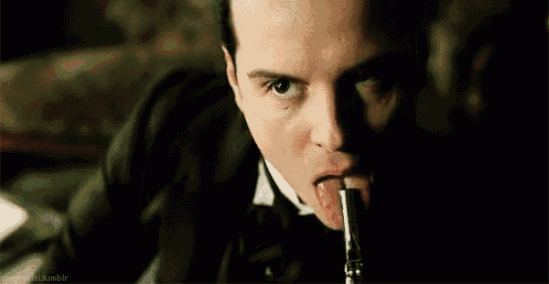 a man in a tuxedo is sticking his tongue out while holding a gun .