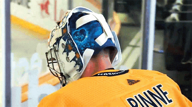 a hockey player wearing a yellow jersey with the name pine on the back