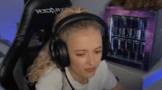 a woman wearing headphones is sitting in a chair in front of a pink fridge .
