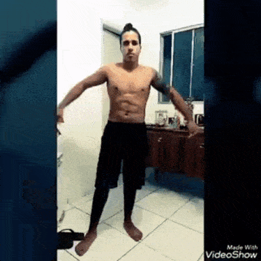 a shirtless man is dancing in a room with his arms outstretched .