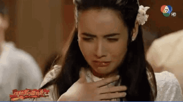 a woman with a flower in her hair is crying in front of a screen with the number 7