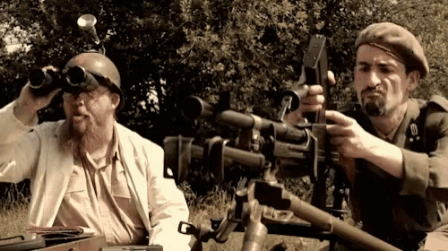 two soldiers looking through binoculars and holding guns
