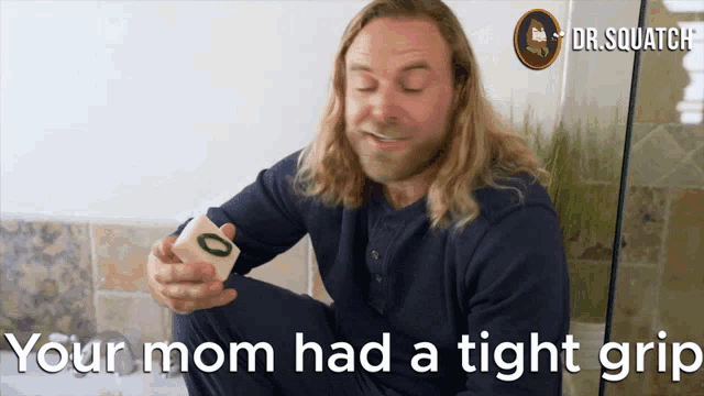 a man holding a block with the words " your mom had a tight grip " above him