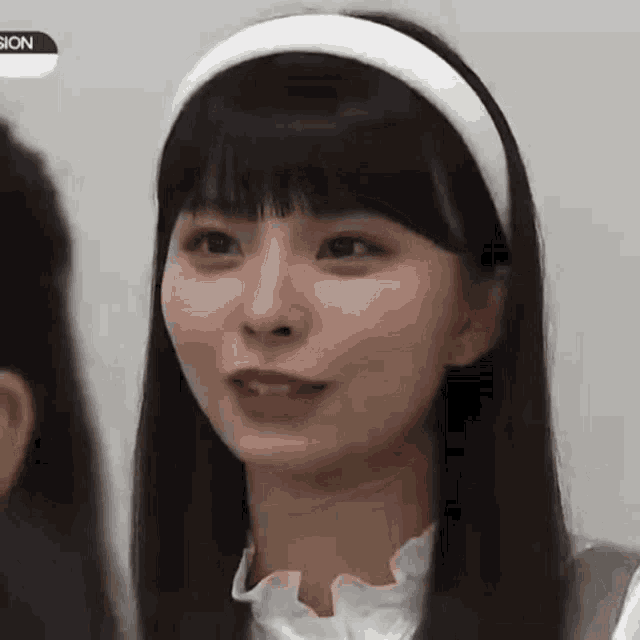 a close up of a girl wearing a white headband and a white shirt .
