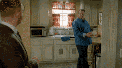 a man in a blue shirt stands in a kitchen