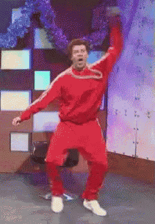a man in a red tracksuit is dancing with his arms in the air