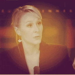 a woman speaking into a microphone in a black jacket