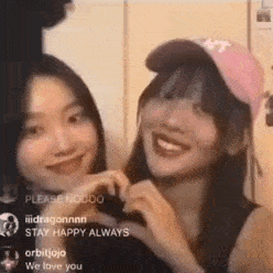 two girls are making a heart with their hands and smiling .