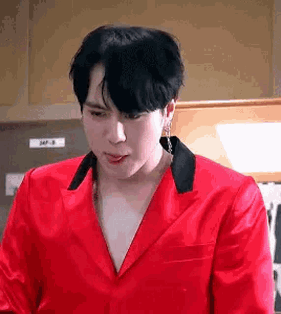 a man in a red jacket with a black collar is sticking out his tongue .