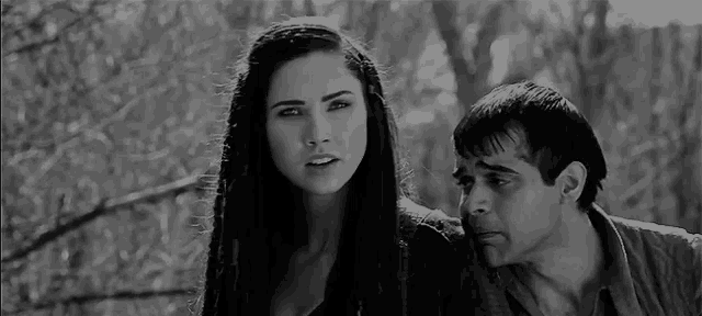 a man and a woman are standing next to each other and looking at each other in a black and white photo .