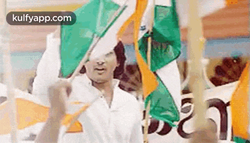 a man in a white shirt is holding a flag in his hand .