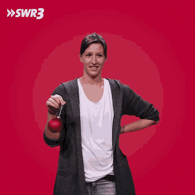 a woman is holding a red ornament in front of a red background with the letters swr3 on it