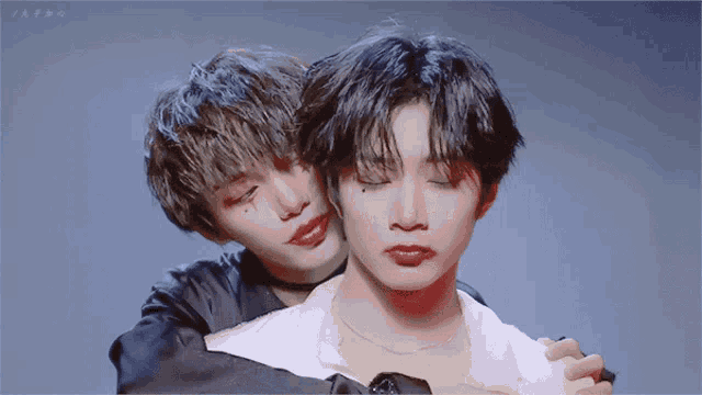 two young men are hugging each other and one has red lipstick on his face