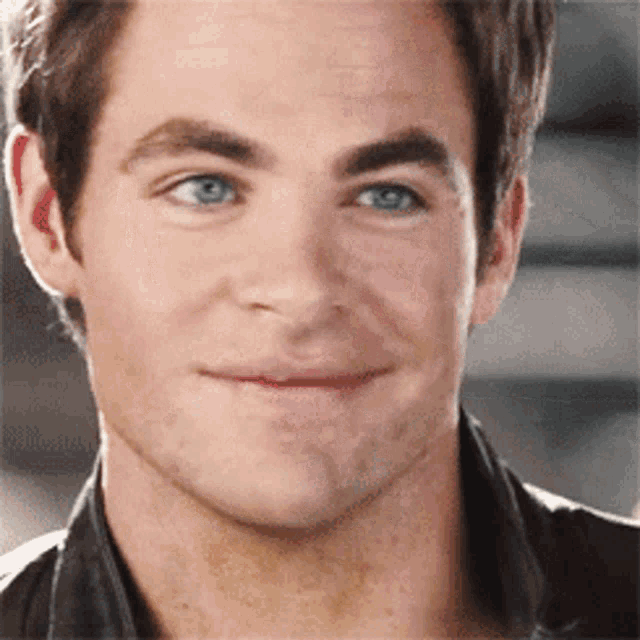 a close up of a man 's face with blue eyes and a smile