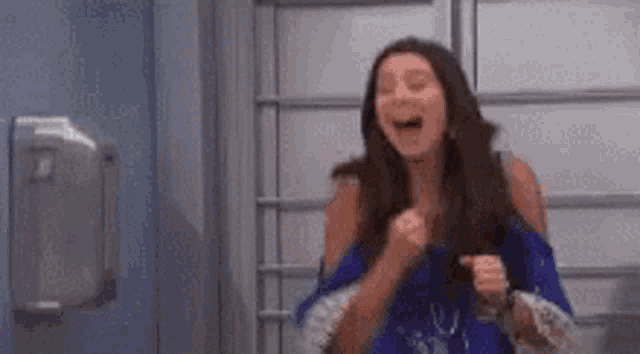 a woman is laughing and holding her fist in the air in a room .