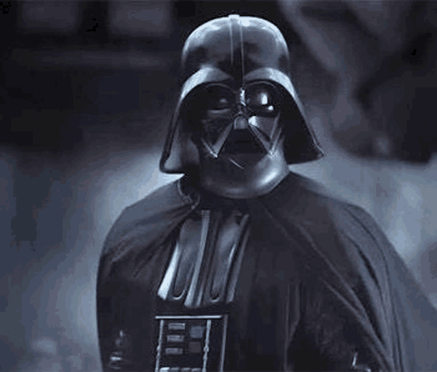darth vader from star wars is wearing a helmet and cape and looking at the camera .