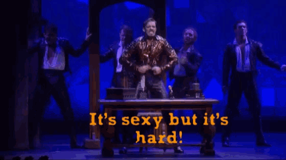 a man without a shirt is standing in front of a table on a stage .