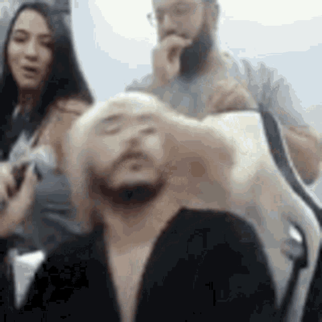 a man with a beard is sitting in front of a woman and a dog .