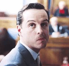 a man in a suit and tie is making a funny face in a courtroom .