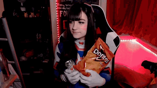 a woman is holding a bag of doritos chips and a can of soda
