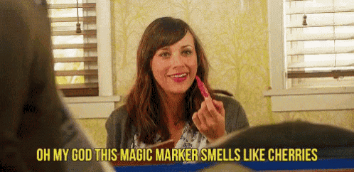 a woman is smiling while holding a marker that smells like cherries ..