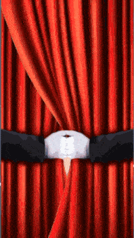 a pair of hands in white gloves are pulling a red curtain