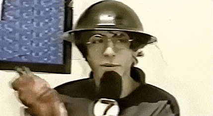 a man wearing a hard hat and glasses is holding a microphone in front of a wall .