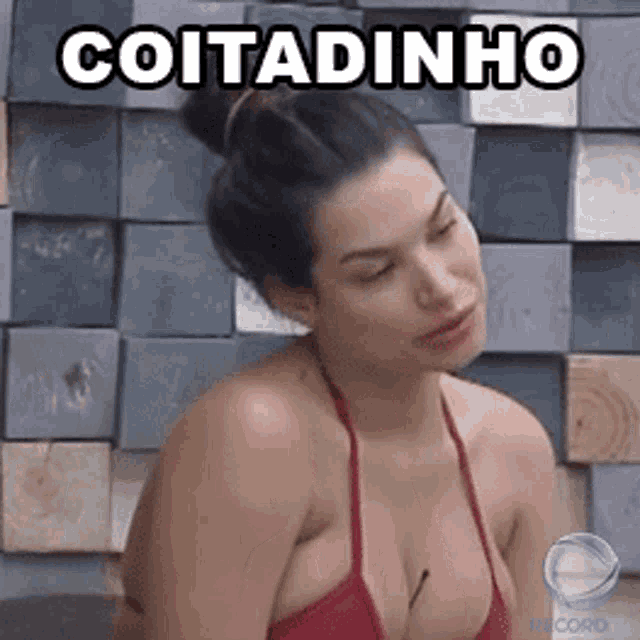 a woman in a red bikini is sitting in front of a wall with the word cotadinho written on it .