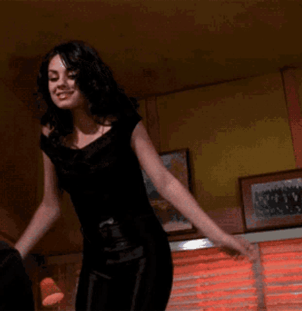 a woman in a black top and black pants is dancing