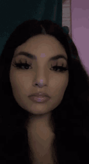 a close up of a woman 's face with long hair and a pink background .