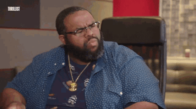 a man wearing glasses and a polka dot shirt is sitting in a chair with the word thrillist on the bottom