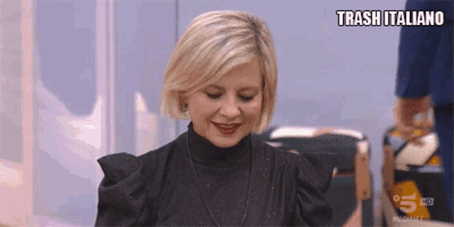 a woman in a black dress is smiling and says trash italiano on the bottom