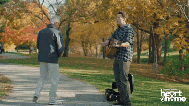 a man playing a guitar in a park with the words heart & home on the bottom right