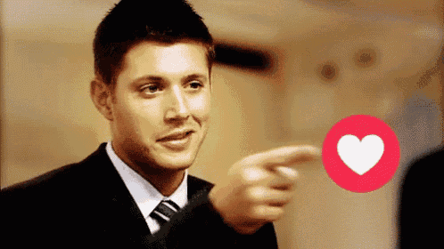 a man in a suit and tie pointing at a heart