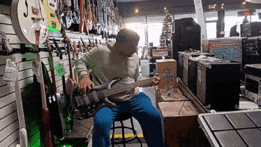 a man is playing a bass guitar in a store with a box that says roland on it