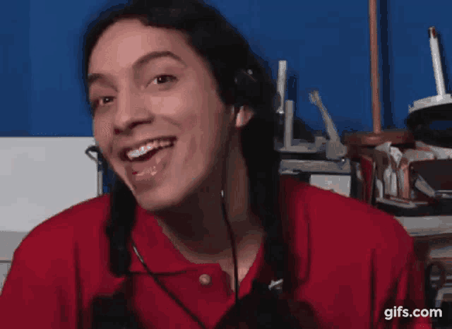 a man in a red shirt is wearing a headset and making a funny face .