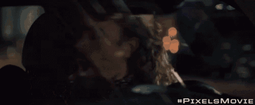 a man is sitting in the back seat of a car with his mouth open and #pixelsmovie written below him