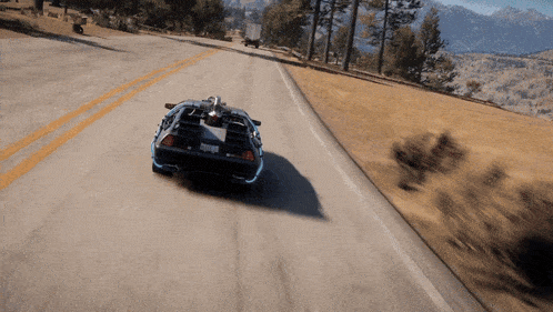 a back to the future car is driving down a road with mountains in the distance