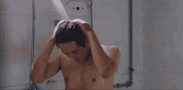 a man without a shirt is taking a shower in a bathroom