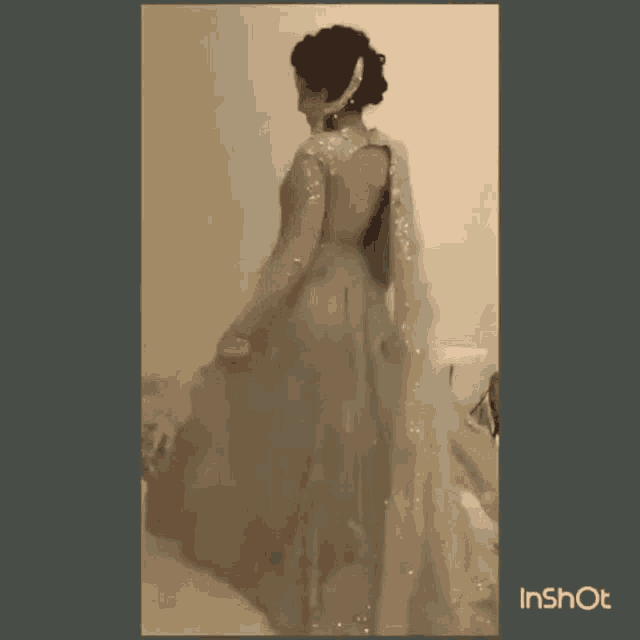 a woman is standing in a room wearing a dress with a sheer back .