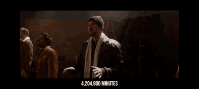 a man with a towel around his neck stands in front of a group of people and says 4,204,800 minutes