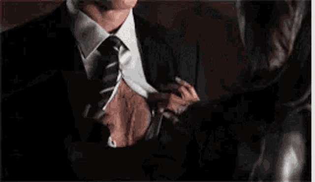 a man in a suit and tie is looking at a woman in a dark room .